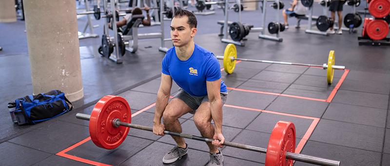 Student lifting a barbell with weights