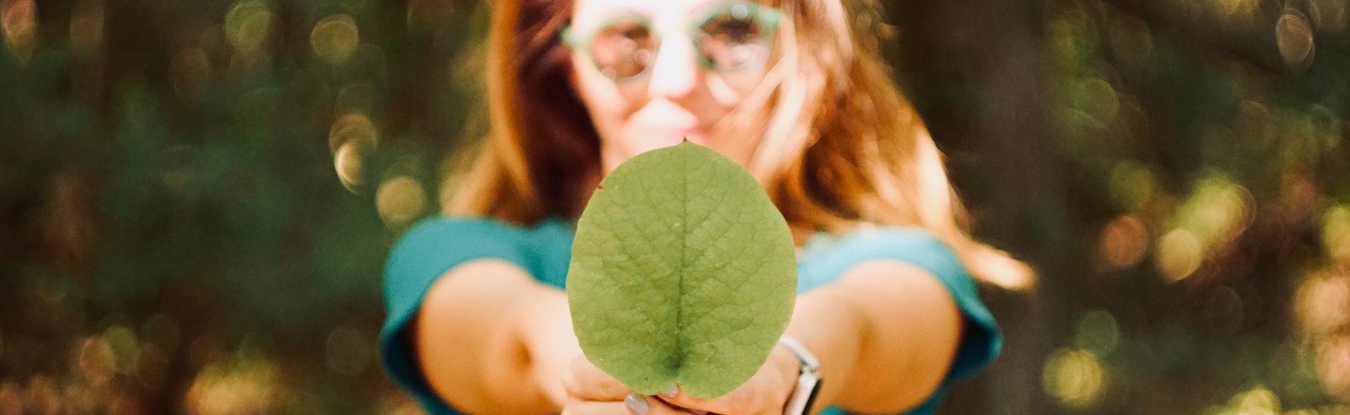 female college student holds a leaf in her hand